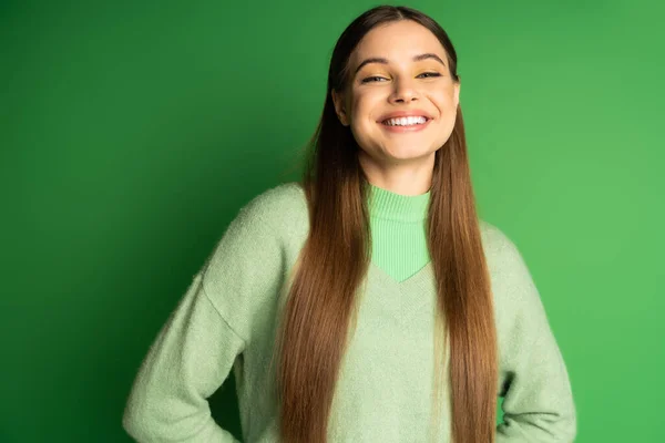 Pleased teen girl in jumper looking at camera on green background — Stock Photo