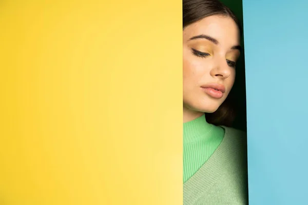 Teenager in jumper standing near blue and yellow background — Stock Photo