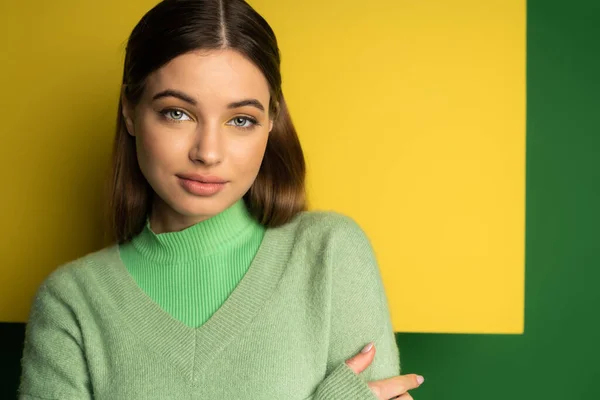 Brunette teen girl in jumper looking at camera on green and yellow background — Fotografia de Stock