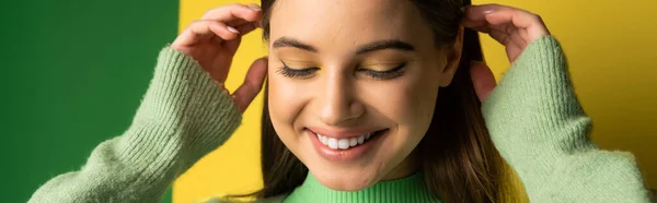 Позитивна дівчина-підліток торкається волосся на зеленому і жовтому тлі, банер — Stock Photo