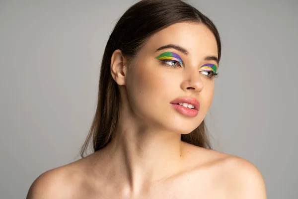 Teen girl with colorful visage and naked shoulders looking away isolated on grey — Stock Photo