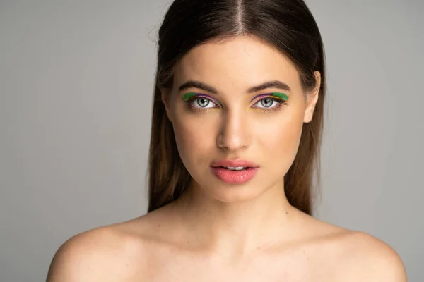 Pretty teenager with multicolored visage looking at camera isolated on grey — Stock Photo