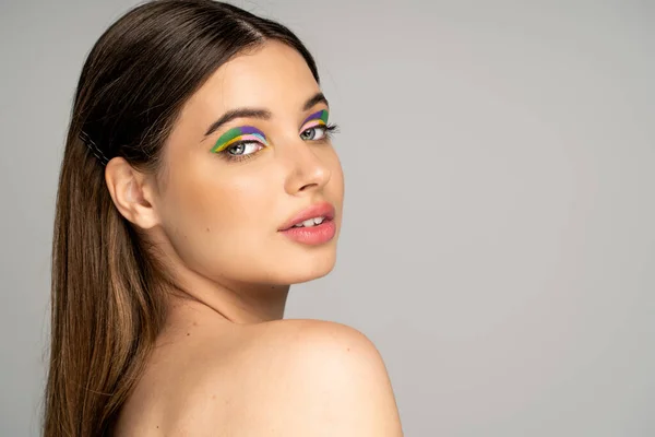 Teen model with colorful makeup looking at camera isolated on grey — Stock Photo