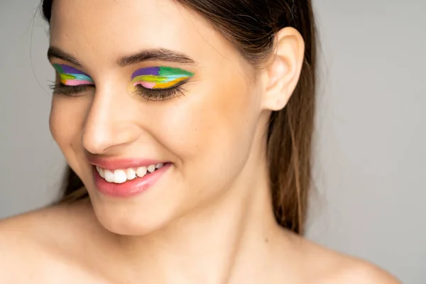 Happy teen model with colorful makeup smiling isolated on grey — Fotografia de Stock