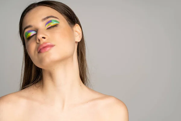 Teen girl with naked shoulders and colorful visage closing eyes isolated on grey — Fotografia de Stock