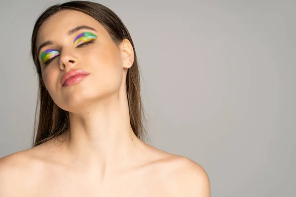 Teen girl with naked shoulders and colorful visage closing eyes isolated on grey — Foto stock