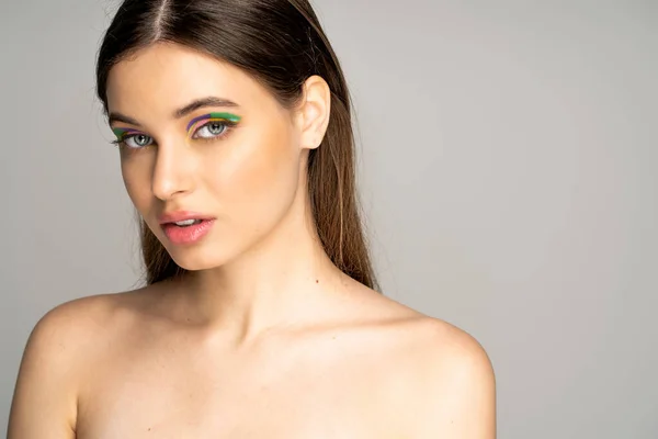 Burette teen girl with colorful eyeshadows and naked shoulders standing isolated on grey — Stock Photo