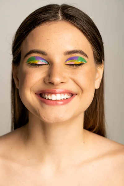 Portrait of freckled teen model with visage smiling with closed eyes isolated on grey — Stock Photo