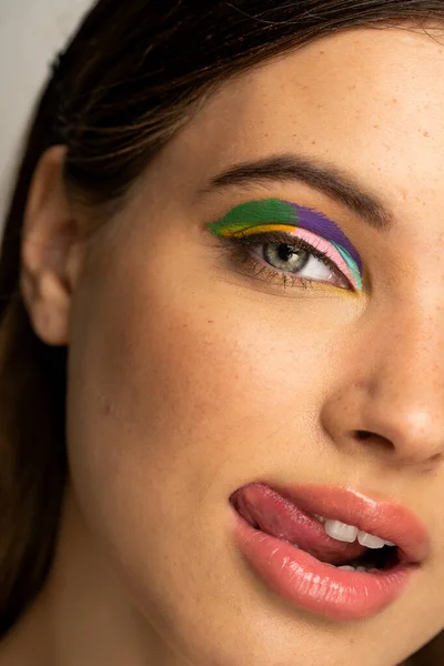 Close up view of teenager with colorful visage sticking out tongue and looking at camera — Stock Photo