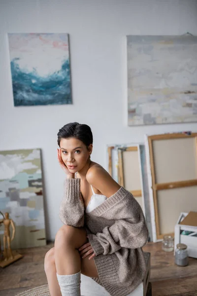 Short haired sexy artist looking at camera while sitting in workshop — Stockfoto