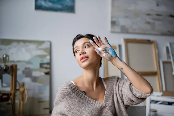 Sexy artist with hand in paint looking away in workshop - foto de stock