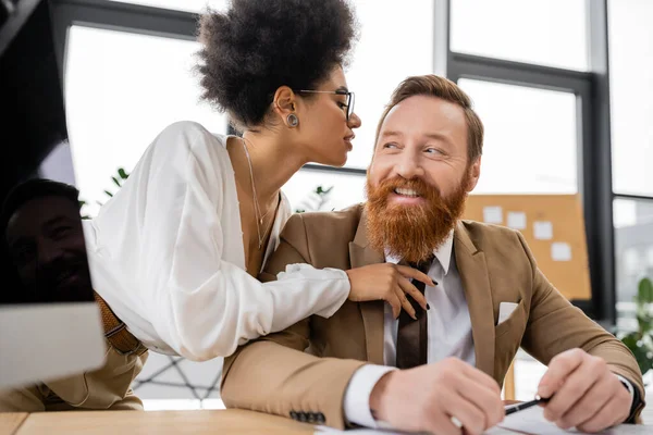 Seductive african american businesswoman hugging while seducing cheerful coworker in office — Photo de stock