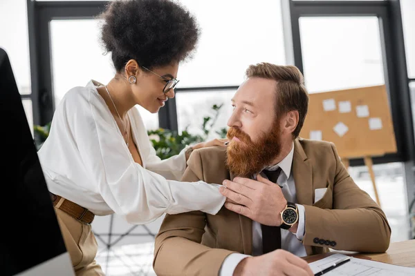 Pleased african american businesswoman looking at cheerful man in office — Stockfoto