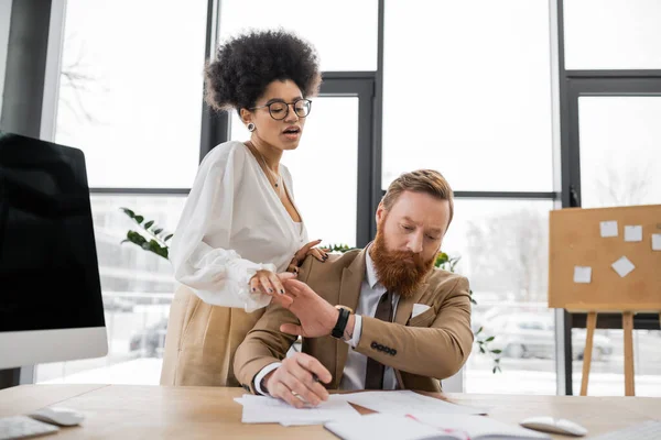Curly african american woman trying to seduce tensed businessman working with documents — Stock Photo