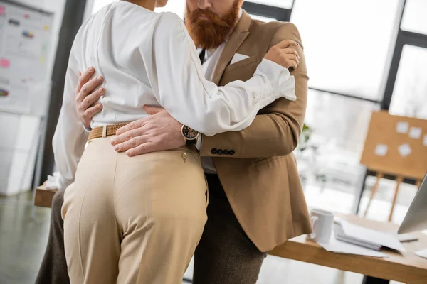 Cropped view of bearded man hugging african american colleague in office — Fotografia de Stock