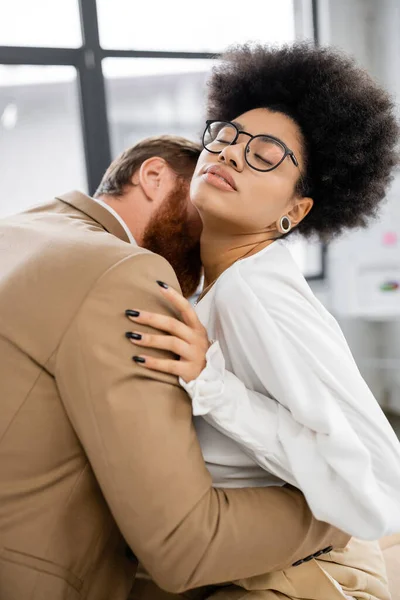 Bearded businessman kissing neck of brunette african american woman in glasses — Photo de stock