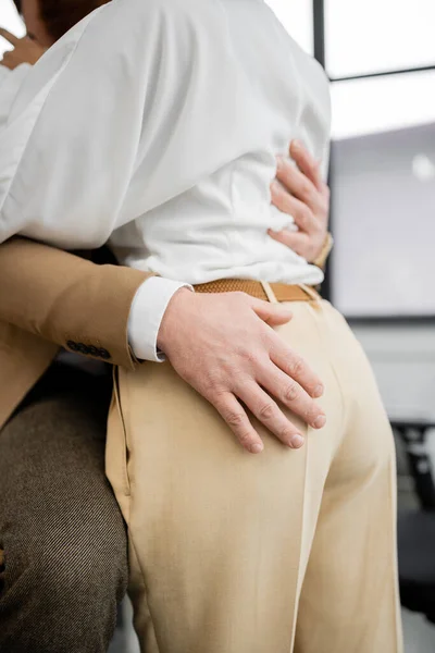 Cropped view of businessman touching buttocks of african american coworker — Stockfoto