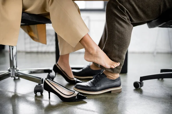 Cropped view of african american woman seducing businessman under desk — Stock Photo