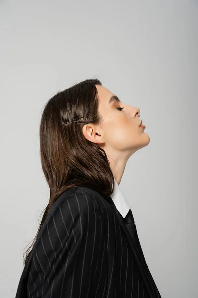 Side view of young brunette woman in black and striped blazer isolated on grey — Fotografia de Stock