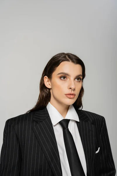 Young brunette woman in trendy formal wear looking away isolated on grey - foto de stock