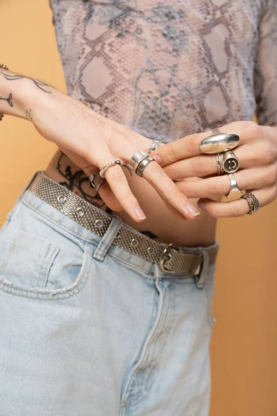 Cropped view of queer person touching rings on fingers isolated on yellow — стоковое фото