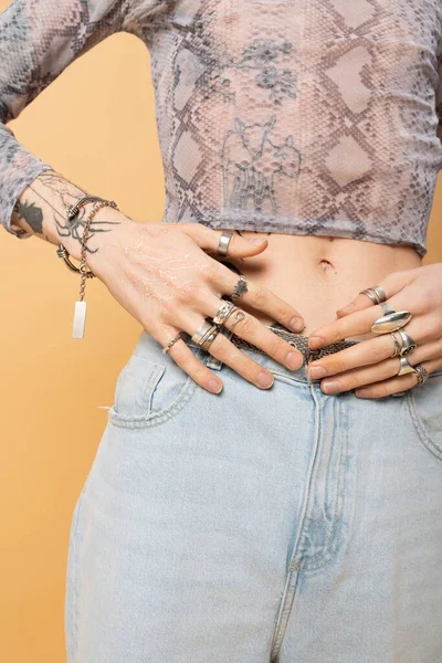 Cropped view of tattooed queer person with accessories isolated on yellow - foto de stock