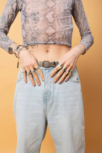 Cropped view of tattooed queer person with accessories isolated on yellow — Photo de stock