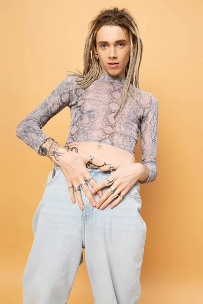 Stylish tattooed queer person posing isolated on yellow — Stock Photo