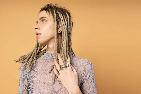 Stylish queer person touching dreadlocks isolated on yellow — Photo de stock