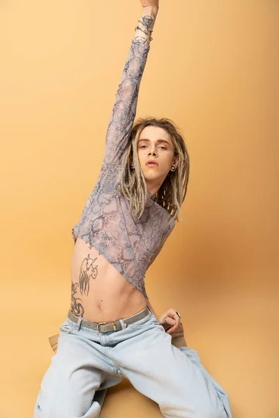 Tattooed queer person in crop top with animal print posing on yellow background — Photo de stock