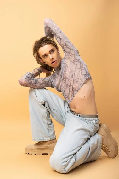 Full length of stylish nonbinary person in jeans and boots posing on yellow background - foto de stock