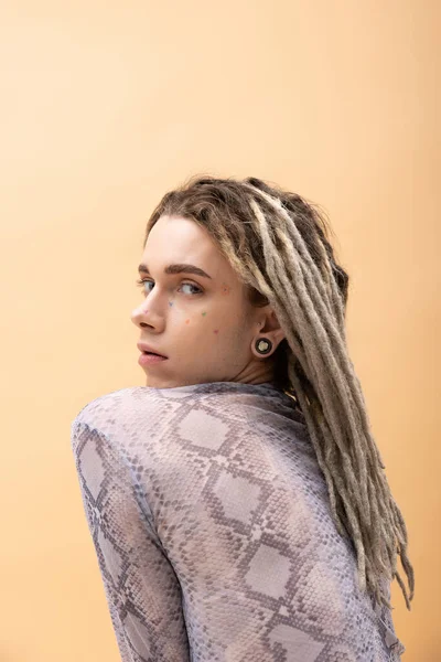 Queer person with dreadlocks looking at camera isolated on yellow — стоковое фото