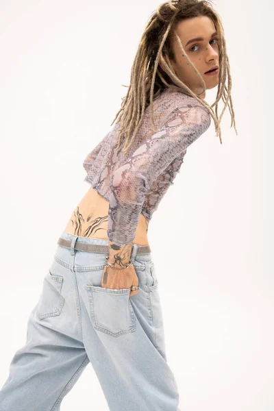 Young queer person with dreadlocks and tattoo posing isolated on white — Photo de stock
