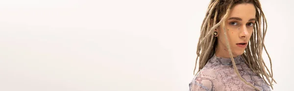 Young tattooed queer person with hairstyle looking at camera isolated on white, banner — Stock Photo