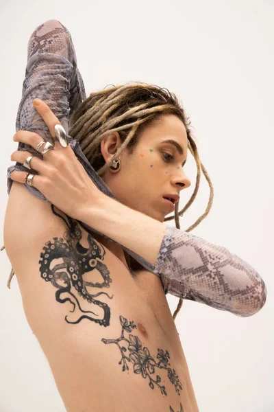 Tattooed queer person in crop top with animal print touching arm isolated on white — Photo de stock
