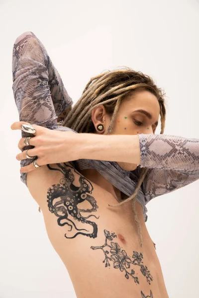 Young tattooed nonbinary person posing in crop top isolated on white — Stock Photo