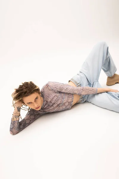 Queer person with dreadlocks lying on white background — Foto stock