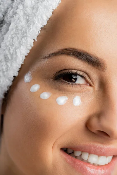 Cropped view of smiling young woman with cosmetic cream on face — стоковое фото