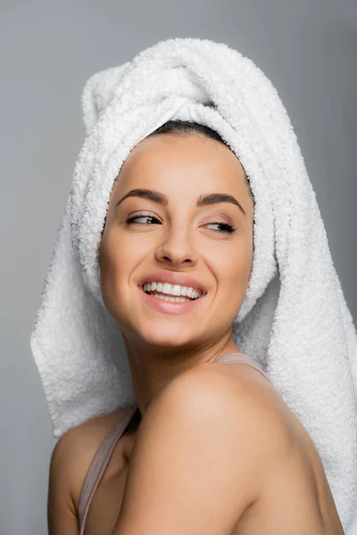 Portrait of cheerful woman with towel on head looking away isolated on grey — Stockfoto