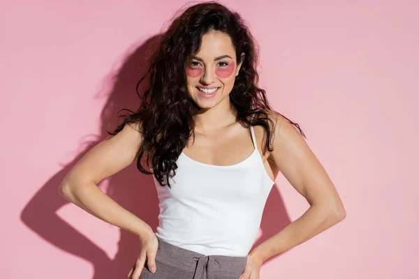 Positive woman with hydrogel eye patches posing on pink background — стоковое фото