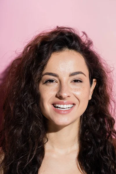Portrait of smiling freckled woman looking at camera on pink background — Stockfoto