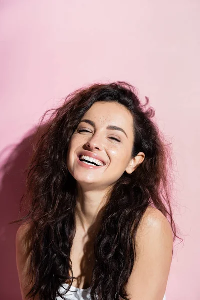 Positive young woman with curly hair looking at camera on pink background — Fotografia de Stock