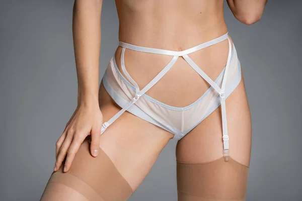 Cropped view of young woman in lingerie and garter belt isolated on grey — стоковое фото