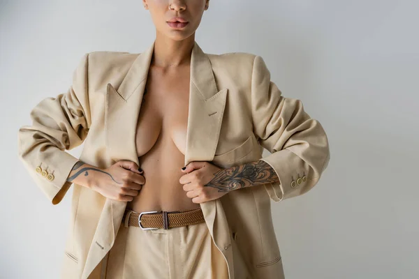 Cropped view of shirtless woman with sexy body posing in elegant oversize suit isolated on grey — Stock Photo