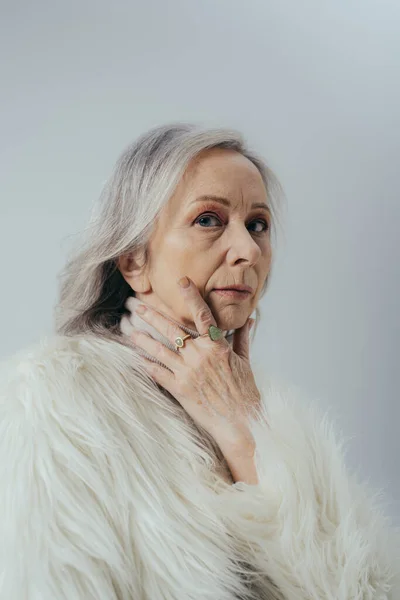 Portrait of senior woman with rings on fingers looking at camera isolated on grey — Stock Photo