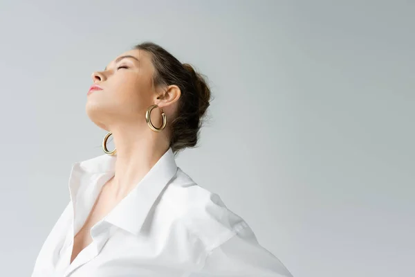 Young sensual woman in white shirt and hoop earrings posing isolated on grey — Fotografia de Stock