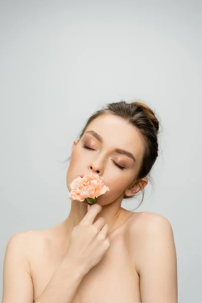 Giovane donna con gli occhi chiusi e il trucco profumato garofano aromatico isolato su grigio — Foto stock