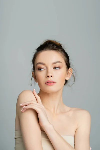Young woman with bare shoulders and natural makeup posing isolated on grey - foto de stock