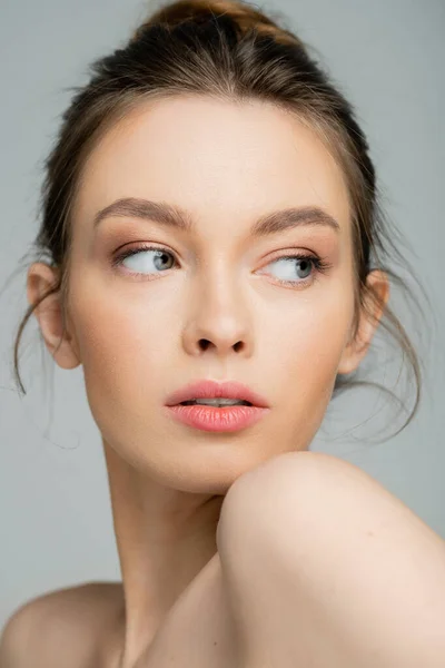 Porträt einer hübschen Frau mit natürlichem Make-up, die isoliert von Grau wegschaut — Stockfoto