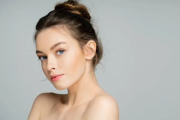 Junge Frau mit natürlichem Make-up blickt in Kamera isoliert auf grau — Stockfoto